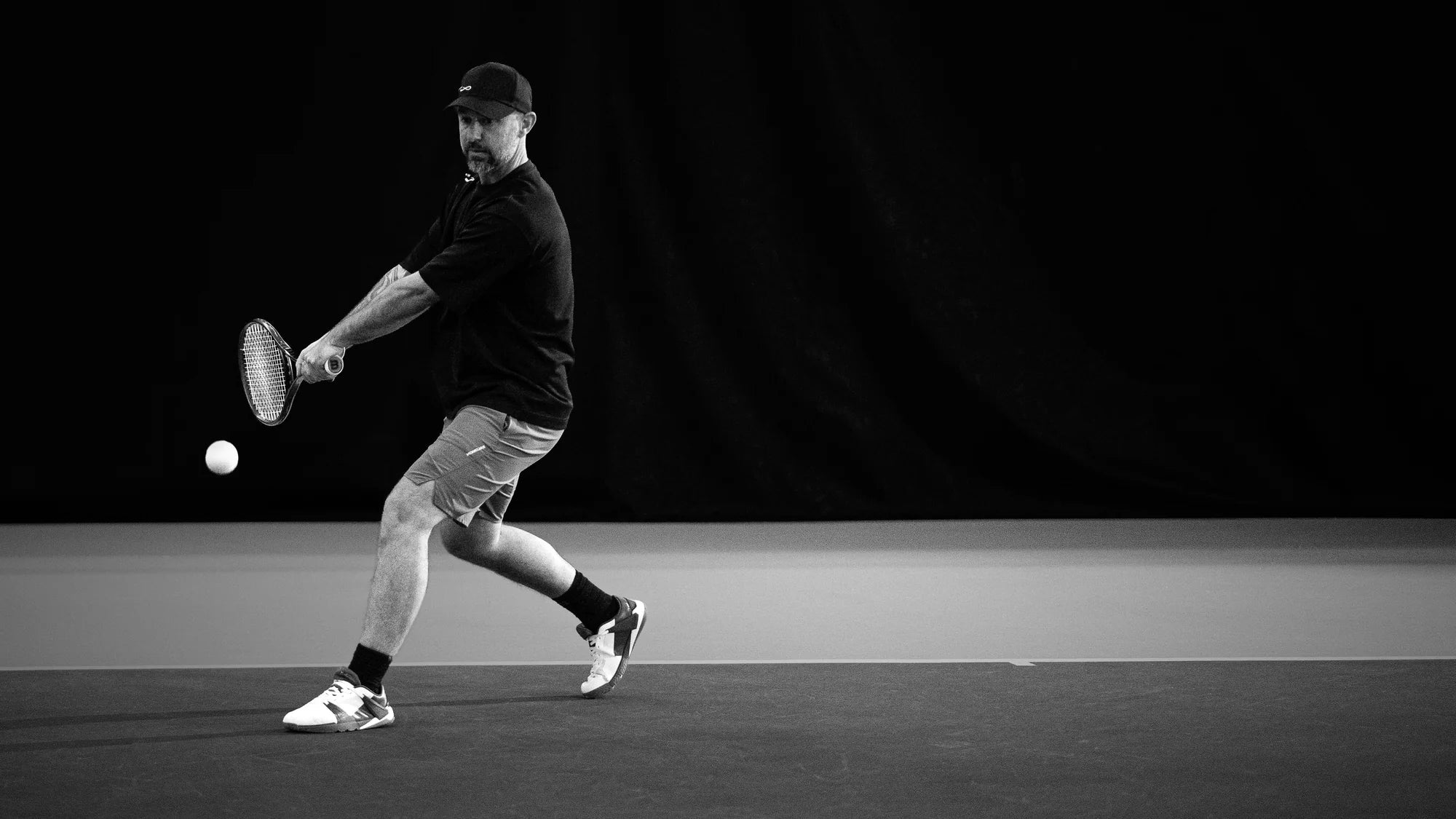 Person playing tennis on a black and white court